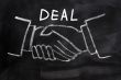 Business deal written on a blackboard background with handshaking