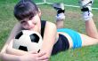 The woman lies on the field with a soccer ball