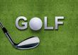 Golf ball and putter on green grass 