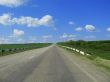 Wide highway and meadow. Clouds over and blue sky