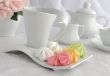 Meringue cookies of different colors on a plate with a cup of co
