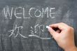 Welcome - word written on a blackboard with a Chinese version