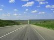 Wide highway and meadow. Clouds over and blue sky