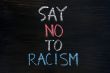 Say no to racism written on a smudged blackboard background