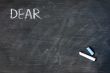 Smudged blackboard background with chalk and the word dear