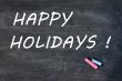 Happy holidays written on a smudged blackboard with chalk