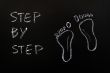 Footprints and the words step by step drawn with chalk