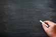 Smudged blackboard background with a hand holding chalk writing.
