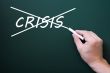 Crossing out crisis on a green chalkboard