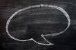 Blank speech bubble drawn on a smudged blackboard