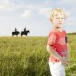 Young blonde boy standing in a grassy field