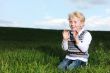Impish little boy kneeling in green field