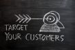 `Target your customers` concept drawn with white chalk on a blackboard