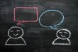 Blank speech bubbles with cartoon figures drawn on a blackboard background