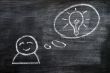 Speech bubble with a man figure and innovation bulb drawn on a blackboard background