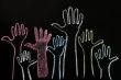 Happy volunteering hands on a blackboard background