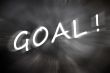 Chalk drawing of `Goal` word written on a blurred chalkboard with motion rays
