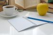 Notebook with a pencil on a table with a cup of coffee and an ap