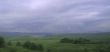 Stormy sky over green field and mountains