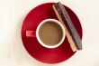 hot chocolate in a cup in red plate with biscuit