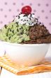 a bowl with chocolate and mint ice cream and cherry on the top