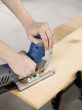 hand using electric jigsaw to cut wooden sheet