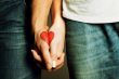 Red heart drawing on hands of couple in love