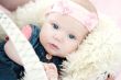 cute newborn baby girl in a basket on white fur 