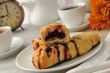 A cup of coffee and a muffin with a cherry