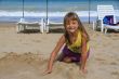 Little six-year-girl playing in the sand on the beach.