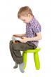 boy with a Tablet PC sitting on a green children`s chair