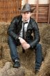Handsome cowboy in leather jacket in the rural interior.