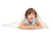 Little girl lying on the floor wrapped in a light blanket and to