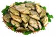 Crucians on a round wattled dish and greens on a white backgroun