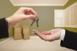 Woman Handing Over the House Keys Inside Empty Green Room
