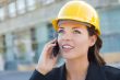 Young Female Contractor Wearing Hard Hat on Site Using Phone