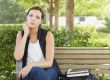 Melancholy Young Adult Woman Sitting on Bench Next to Books