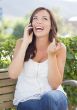 Young Adult Female Talking on Cell Phone Outdoors on Bench