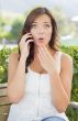 Shocked Young Adult Female Talking on Cell Phone Outdoors