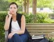 Melancholy Young Adult Woman Sitting on Bench Next to Books