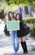 Excited Mixed Race Female Students Holding Blank Chalkboard