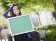 Excited Mixed Race Female Student Holding Blank Chalkboard