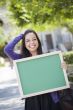 Excited Mixed Race Female Student Holding Blank Chalkboard