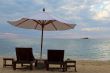 Two beds and an umbrella on the beach at sunset
