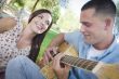 Mixed Race Couple at the Park Playing Guitar and Singing