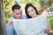 Lost and Confused Mixed Race Couple Looking Over Map Outside
