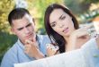 Lost and Confused Mixed Race Couple Looking Over Map Outside