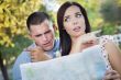 Lost and Confused Mixed Race Couple Looking Over Map Outside
