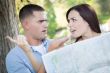 Lost and Confused Mixed Race Couple Looking Over Map Outside