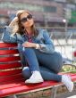 girl in jeans sitting on a bench in the street